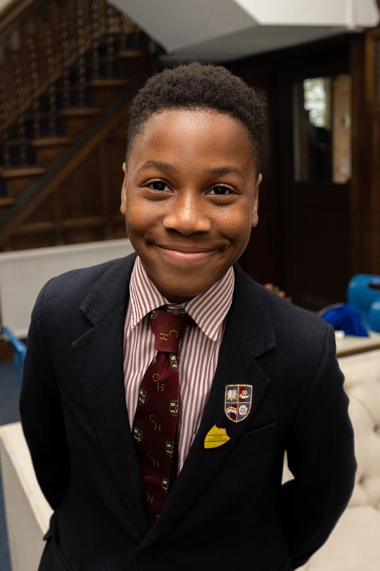 A young boy in a school uniform smiling, radiating confidence and happiness