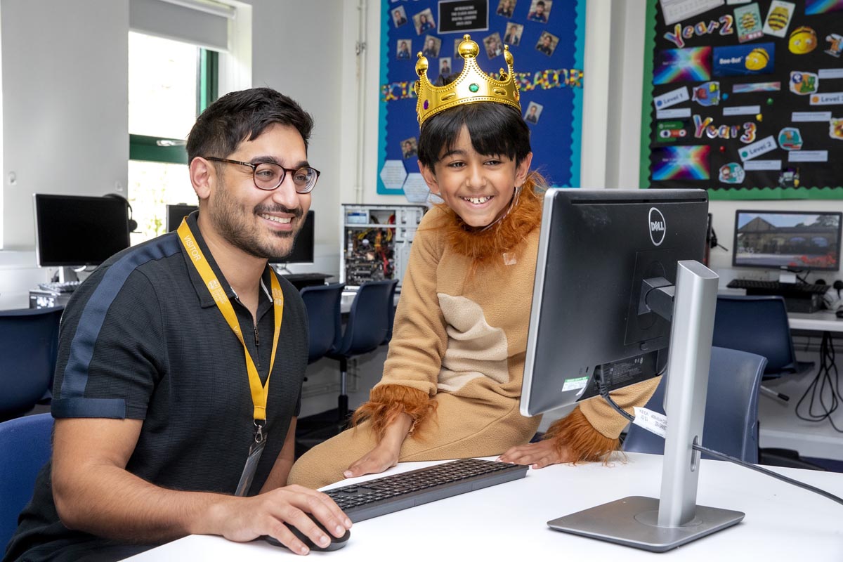 A man and child in a lion costume and crown smiling at a computer screen