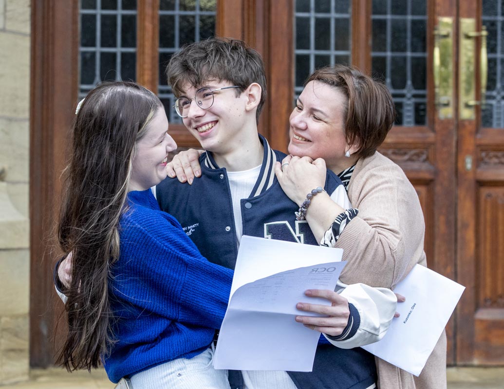 A family smiling holding GCSE result papers