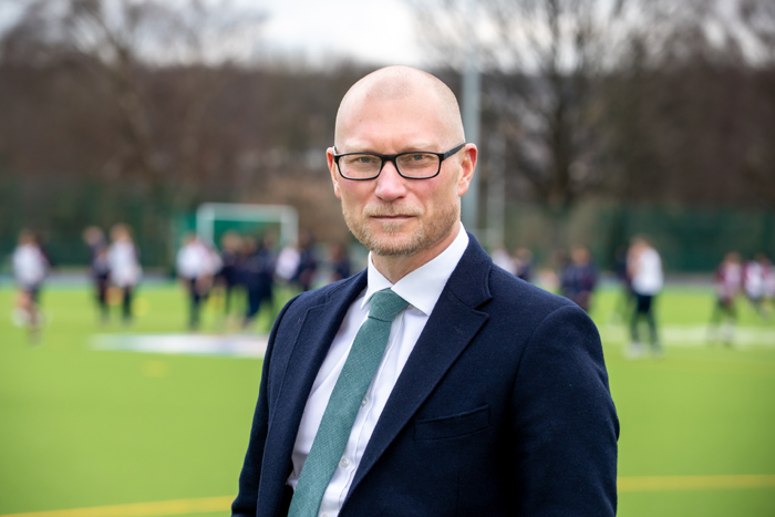 Head Teacher Simon stood on a sports field